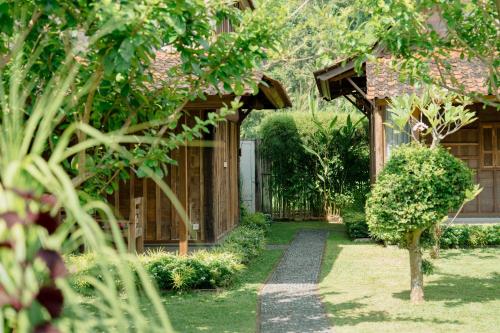 a garden with a house with a gate and a pathway at Kubu Sakian Villa and Restaurant Sidemen in Silebeng