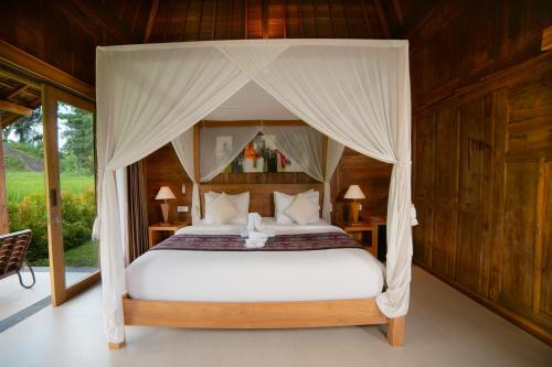 a bedroom with a bed with a canopy at Kubu Sakian Villa and Restaurant Sidemen in Silebeng