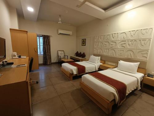 a hotel room with two beds and a television at Classic Boutique Hotel & Luxury Service Apartments in Visakhapatnam