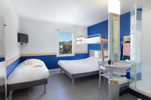 een ziekenhuiskamer met 2 bedden en een wastafel bij ibis budget Saint-Maximin in Saint-Maximin-la-Sainte-Baume