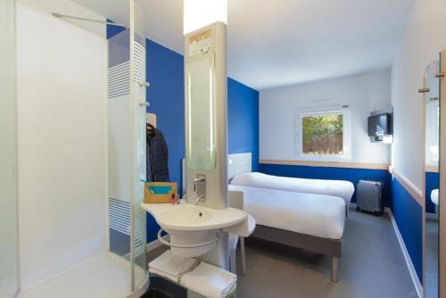a bathroom with two beds and a sink and a shower at ibis budget Saint-Maximin in Saint-Maximin-la-Sainte-Baume