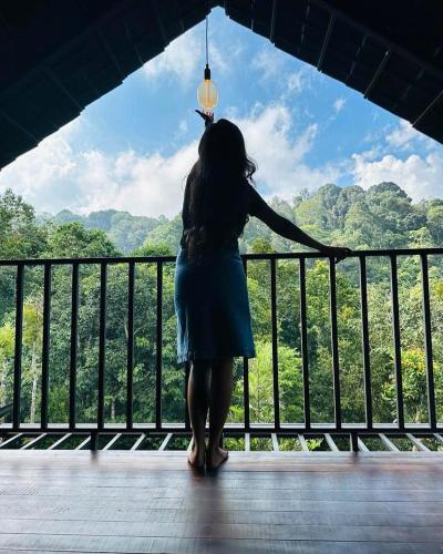 a woman standing on a balcony looking out at the forest at Tree House Wayanad in Muthanga