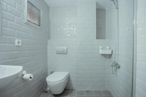 a white bathroom with a toilet and a shower at Deniz Pansiyon in İzmir