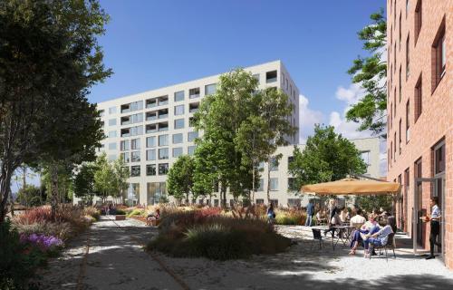 people sitting under an umbrella in front of a building at IntercityHotel Breda in Breda