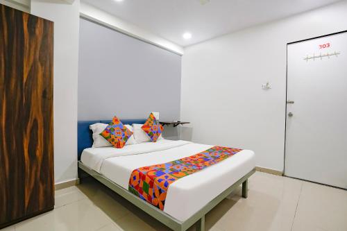 a white room with a bed with colorful pillows at FabExpress Blue Stone in Surat