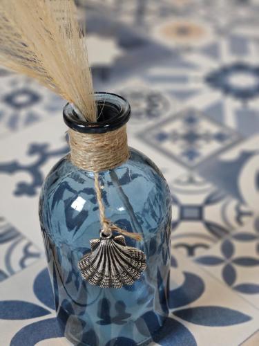 a blue glass jar with a feather sticking out of it at La Maison du pêcheur - Jacuzzi 3 Etoiles in Jard-sur-Mer