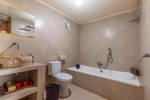 a bathroom with a toilet and a tub and a sink at Daghan Cottage Nusa Penida in Nusa Penida