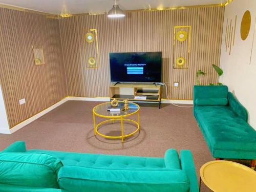 ein Wohnzimmer mit einem blauen Sofa und einem TV in der Unterkunft Jesse 2 Bedroom Apartment by GET in Dunstable