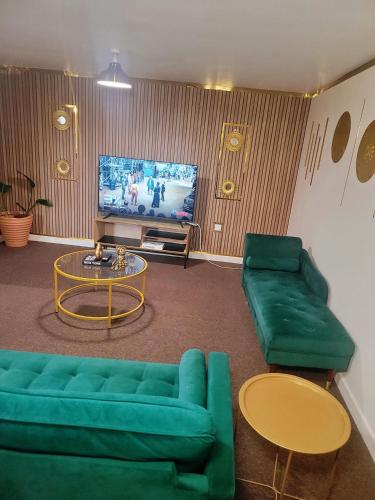 ein Wohnzimmer mit 2 grünen Sofas und einem TV in der Unterkunft Jesse 2 Bedroom Apartment by GET in Dunstable