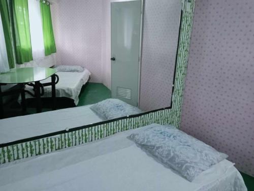 a mirror in a room with two beds and a table at QUICKSHIELD HOMESTAY in Naga