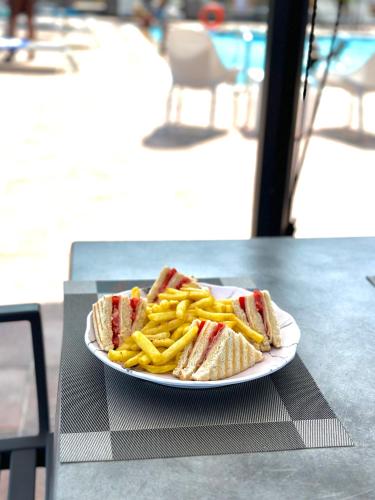 a plate with a sandwich and french fries on a table at Harma Corfu in Sidari