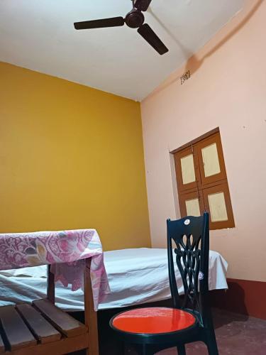 a bedroom with a ceiling fan and a chair and a bed at Niraloy in Bolpur