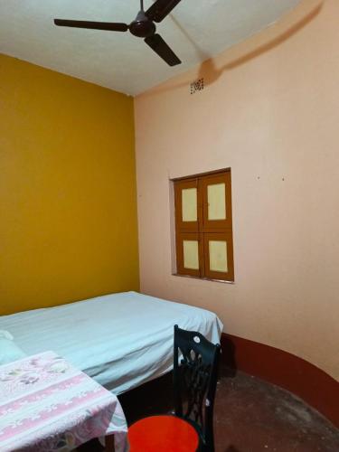1 dormitorio con 1 cama y ventilador de techo en Niraloy en Bolpur