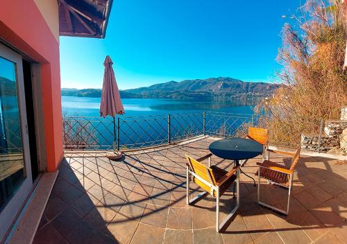 een patio met een tafel en stoelen en een parasol bij Lake view rooms and flats Casa Sul Lago in Orta San Giulio