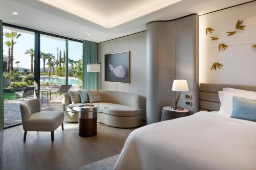 チェシメにあるReges, a Luxury Collection Resort & Spa, Cesmeのベッドルーム1室(ベッド1台付)、リビングルームが備わります。