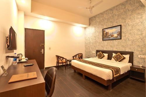 a hotel room with a bed and a table and a desk at Luxury Tashree Hotel at Airport in New Delhi