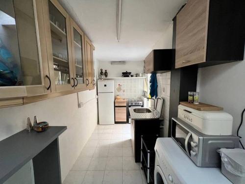 eine kleine Küche mit weißen Geräten und Holzschränken in der Unterkunft Graswald, 1 bedroom accommodation in Gżira