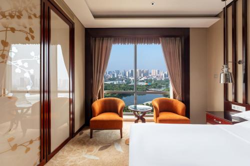 a bedroom with a bed and two chairs and a table at Sheraton Changde Wuling Hotel in Changde