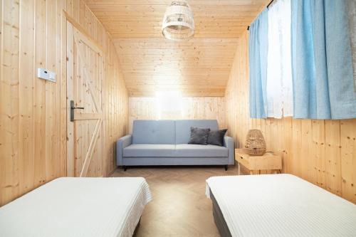 a room with two beds and a blue couch at Siedlisko Złota Góra domki całoroczne na Kaszubach in Brodnica