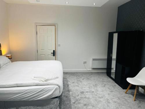 a bedroom with a white bed and a black cabinet at OYO The Pleasant House in Manchester