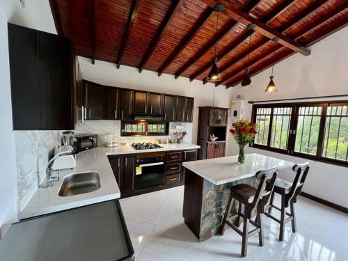 uma cozinha com uma ilha com cadeiras e um balcão em Acogedora casa de campo con excelente ubicación em Carmen de Viboral