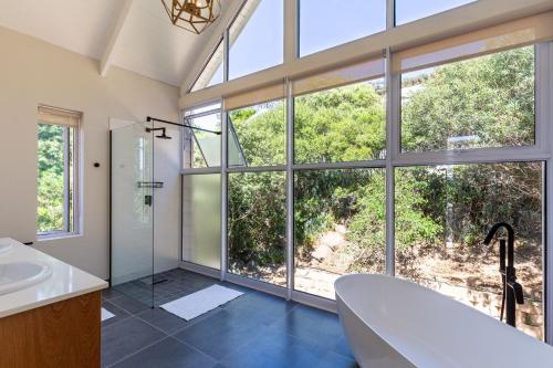 ein Badezimmer mit einem großen Fenster und einer Badewanne in der Unterkunft Elite Retreats -Forest Villa C, back up power for load shedding in Kapstadt