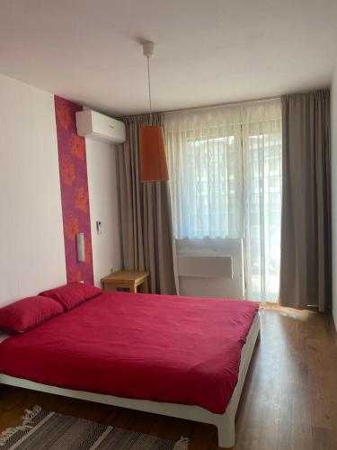 une chambre avec un lit rouge et une fenêtre dans l'établissement Neon Gondola apartment, à Bansko