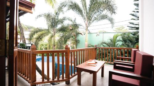 a balcony with a table and chairs and palm trees at Daffodil Restaurant & Holiday Resort in Unawatuna
