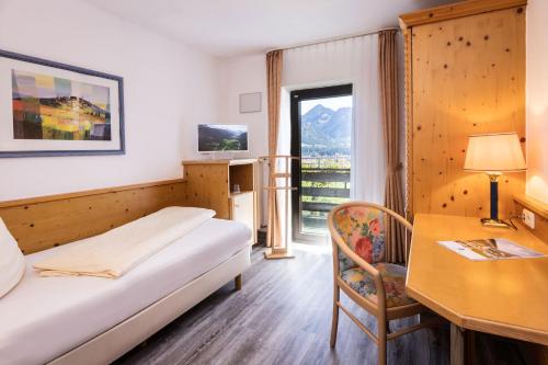 a hotel room with a bed and a desk and a window at Allgäuer Bergbad in Oberstdorf