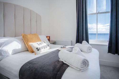 a bedroom with two beds with towels and a window at Caldey View - Luxury 2 Bedroom - Panorama - Tenby in Tenby