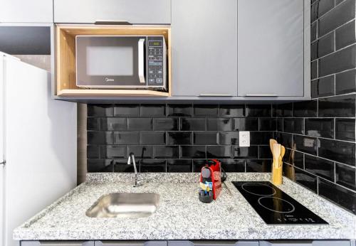 a kitchen with a sink and a microwave at Easy Star - Lindo Studio próx.Metrô Ana Rosa - LN02H in Sao Paulo