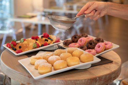 a table with three plates of pastries and a person holding a spoon at Relais dell'Olmo in Perugia