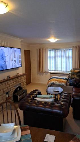 a living room with a leather couch and a tv at Double rooms available, near Safari Park & Hospital in Franche