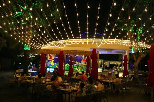 a restaurant with people sitting at tables with lights at Ramada Plaza by Wyndham Sanya Bay in Sanya