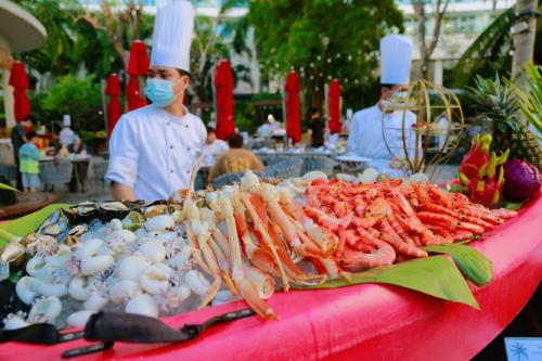 a buffet of food with people wearing face masks at Ramada Plaza by Wyndham Sanya Bay in Sanya