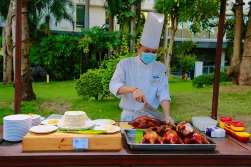 a chef preparing meat on a table with a grill at Ramada Plaza by Wyndham Sanya Bay in Sanya