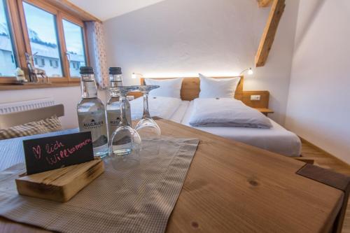 a room with two beds and a table with two wine bottles at Gasthof Hirsch Vorderburg in Rettenberg