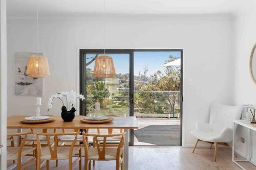 comedor con mesa de madera y sillas en Terrigal Beach House, en Terrigal