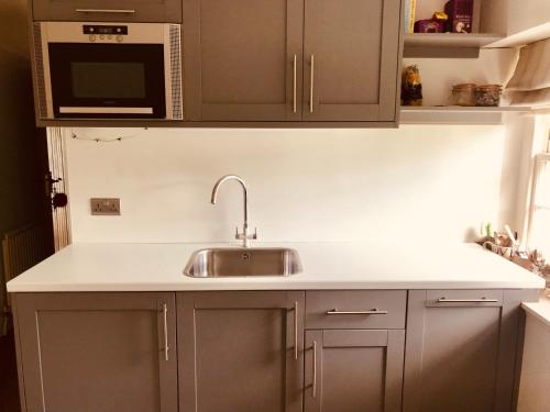a kitchen with a sink and a microwave at The Old Post Office Studio Apartment in a Beautiful Cotswold Village in Cirencester
