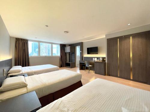 Habitación de hotel con 3 camas y escritorio. en Hotel Imperial, en Kuala Lumpur