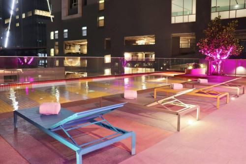 a pool with tables and chairs in front of a building at The Quarter Ratchathewi by UHG in Bangkok