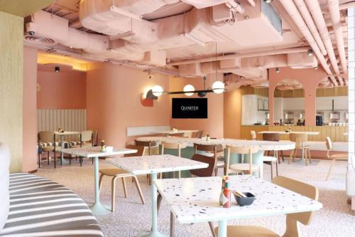 a restaurant with tables and chairs and a projection screen at The Quarter Ratchathewi by UHG in Bangkok