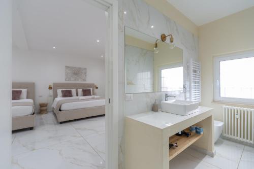 a white bathroom with a sink and a bedroom at Leia Hospitality in Milan
