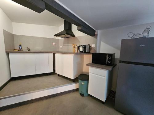 eine Küche mit weißen Schränken und einem schwarzen Kühlschrank in der Unterkunft Maison Allauch La Gloire de mon Père in Allauch