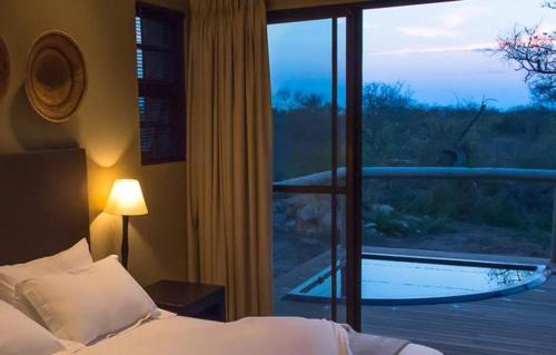 Schlafzimmer mit einem Bett und einem großen Glasfenster in der Unterkunft Mjejane Luxury Self-Catering Villa in Hectorspruit