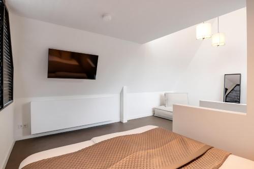 a white room with a bed and a tv at The Slow in Zuidoostbeemster