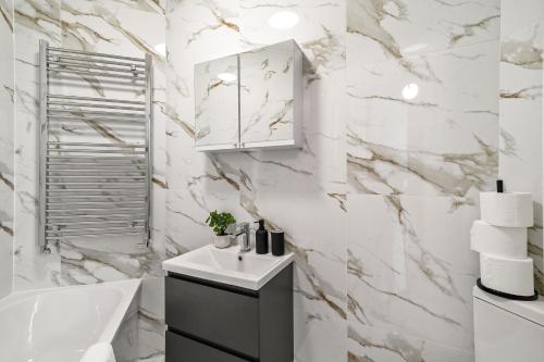 a bathroom with white marble walls and a sink and a tub at LiveStay - London Chiswick Apartments with Free Parking in London