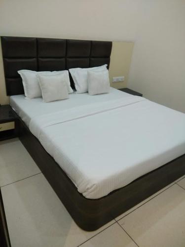 a large bed with white sheets and pillows at Kesari root in Amritsar