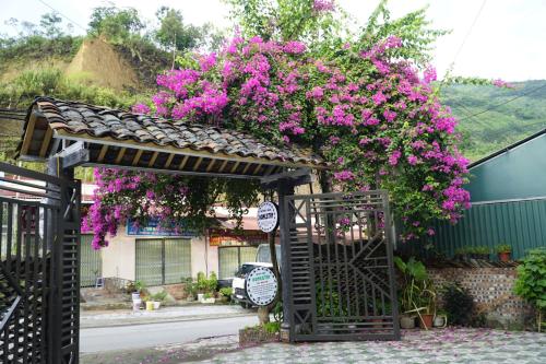 uma entrada para uma casa com flores cor-de-rosa em Nung Gia Homestay em Xin Man