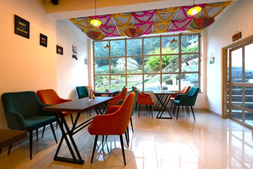 a restaurant with tables and chairs and a large window at Chopta House Hotel and Restaurant in Sari